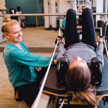 woman exercising next to physical therapist