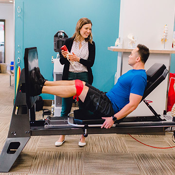 man exercising next to physical therapist